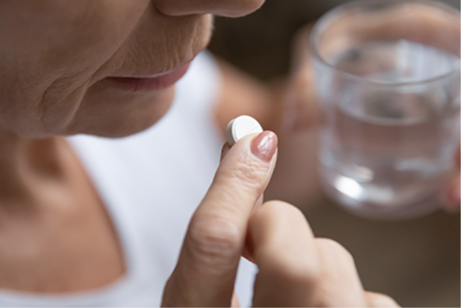 אישה מבוגרת נוטלת תרופה לטיפול במחלה שהתפתחה עקב הזקנה